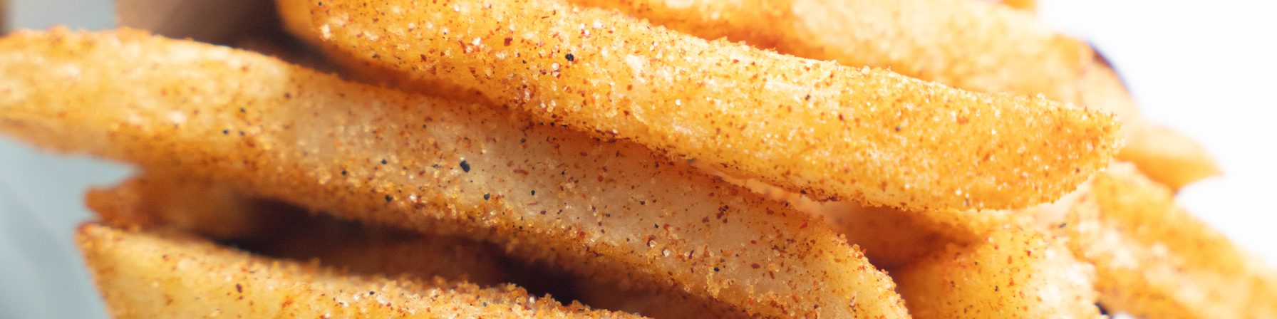 Close-up of Goldies golden fries dusted with house seasoning in a takeout box